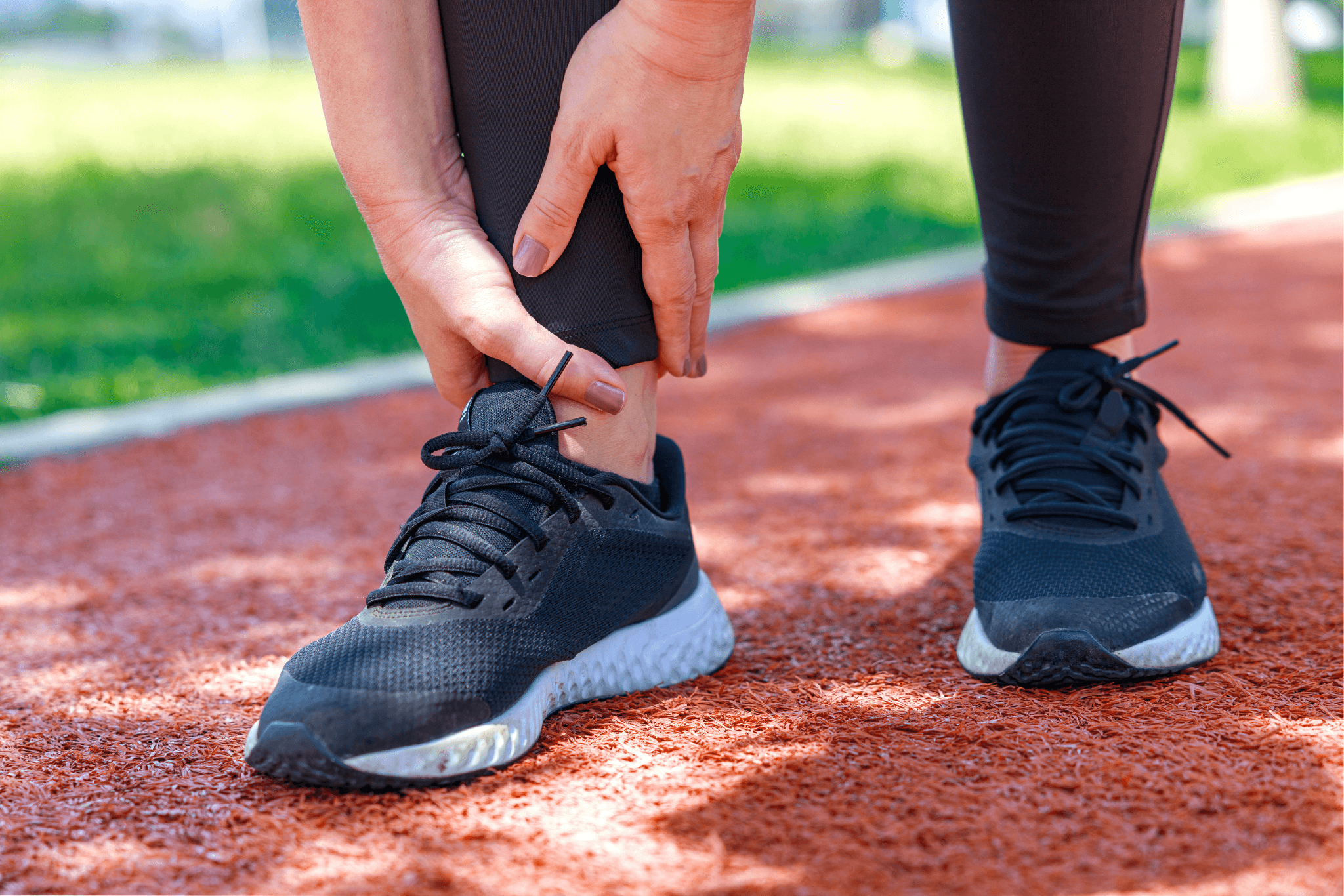Injury from workout: Young woman use hands hold on her ankle while running on track field.